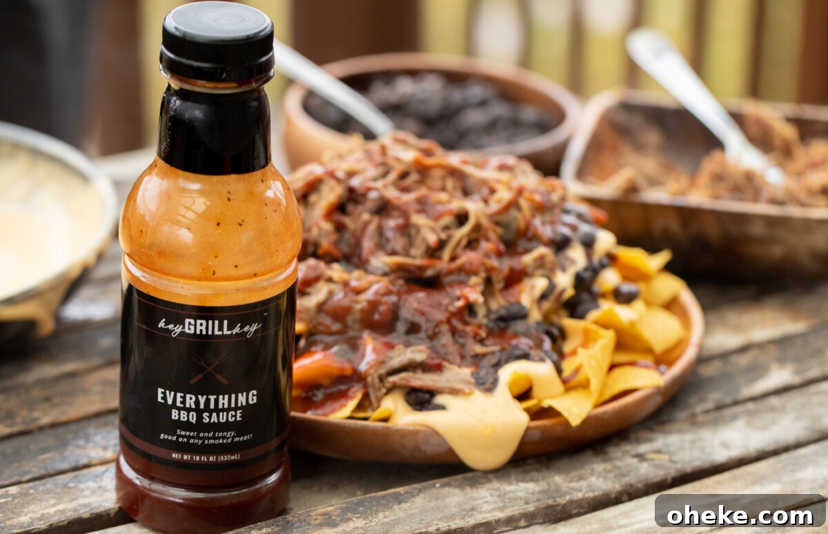 How to Store, Reheat, and Repurpose BBQ Leftovers 9 Bottle of Hey Grill Hey Everything Sauce in the foreground with a plate of pulled pork nachos in the background.