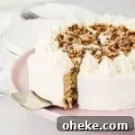 cake server taking a slice of cake mix hummingbird cake off of a cake stand with a stack of plates in the background