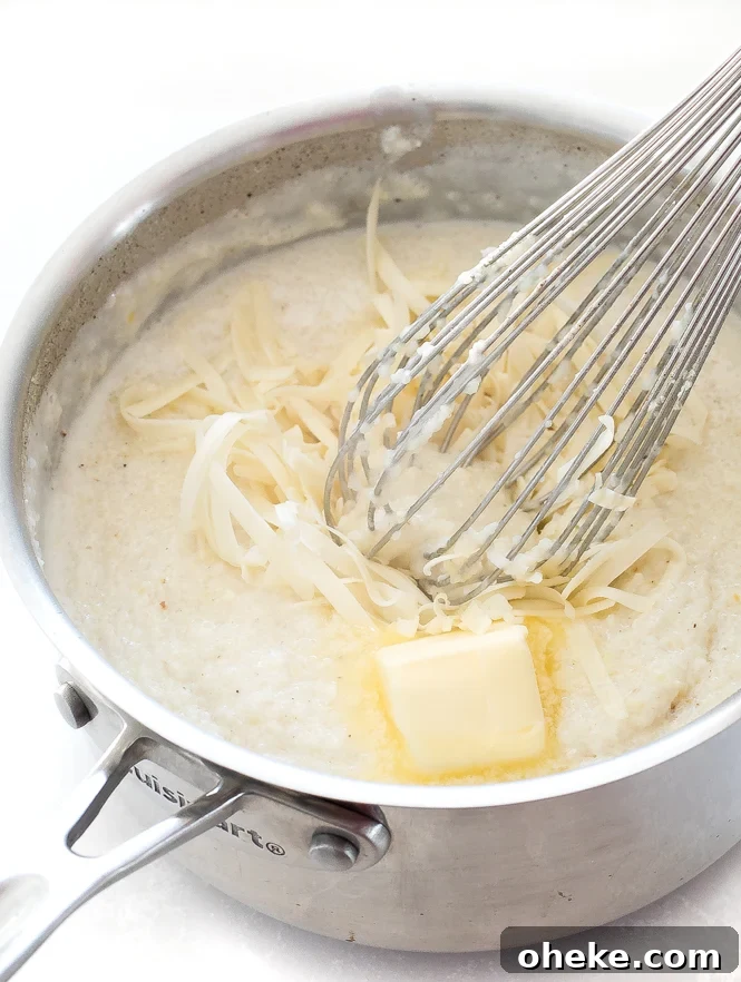 Grits with butter and cheese in a saucepan with a whisk.