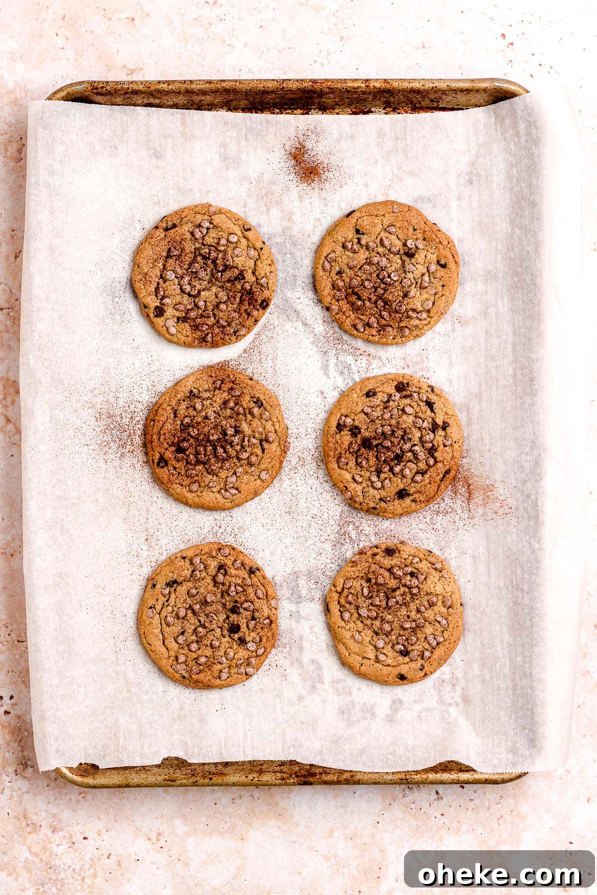Cinnamon chocolate chip cookies on a parchment lined baking sheet.