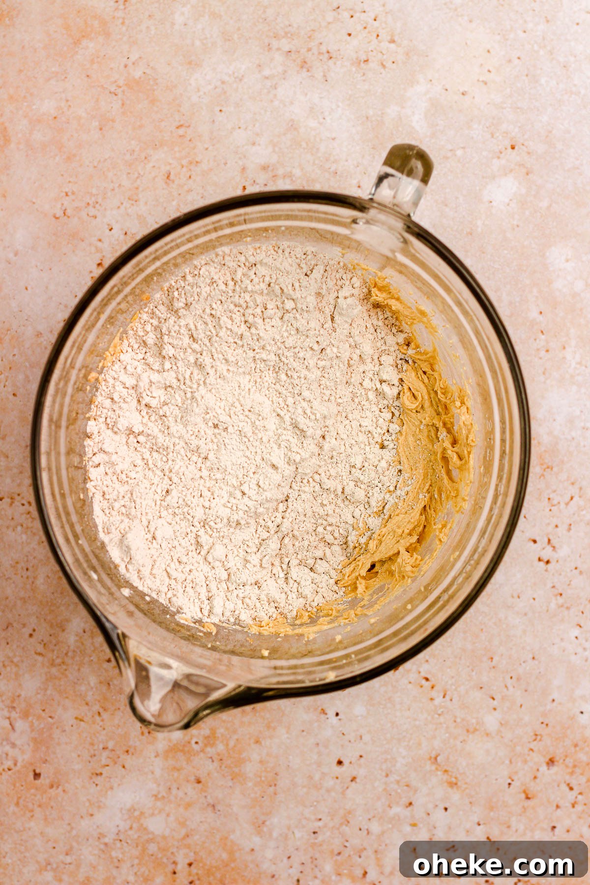 A glass bowl with cookie dough and flour.