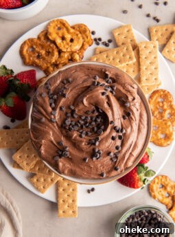 brownie batter dip in a bowl on a plate with graham crackers, pretzel things and strawberries.