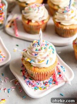 small plate with funfetti cupcake topped with vanilla frosting, sprinkles and a birthday candle.