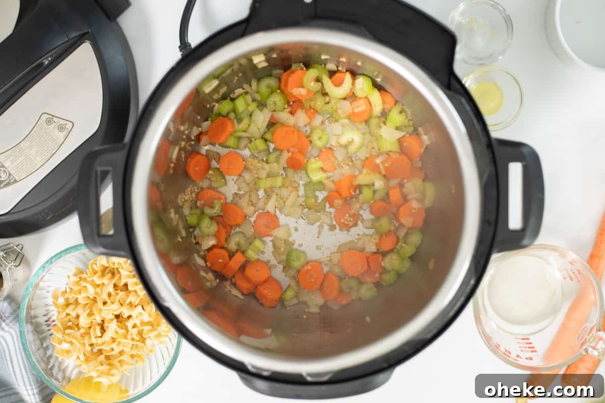 Carrots, onions, celery, and garlic sauteed in pressure cooker with olive oil and butter and ingredients for turkey noodle soup in background.