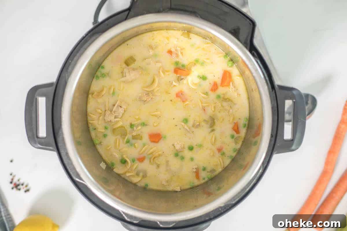 Creamy turkey noodle soup in inner pot of instant pot next to carrots and celery.