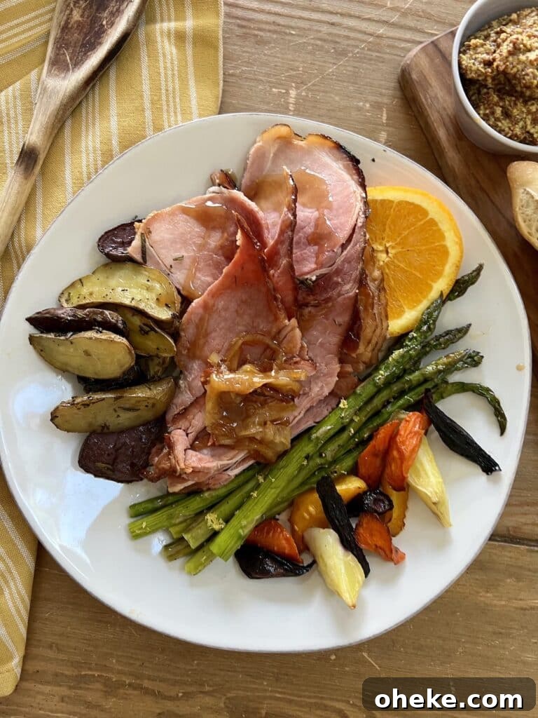Dutch Oven Spiral Ham with Marsala Glaze Recipe 7 Baked spiral ham plated on a white dinner plate with asparagus, potatoes and carrots, surrounded by wooden spoon on yellow towel and mustard.