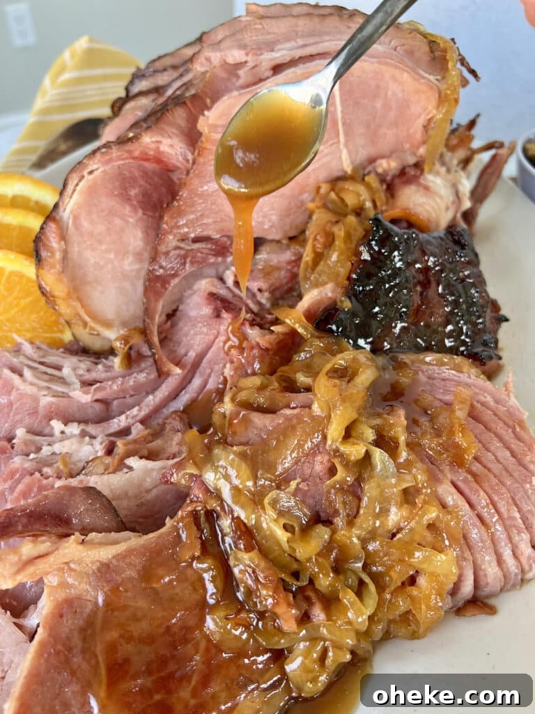 Dutch Oven Spiral Ham with Marsala Glaze Recipe 9 Baked ham in a dutch oven plated on an oval platter with additional marsala glaze being drizzled over it.