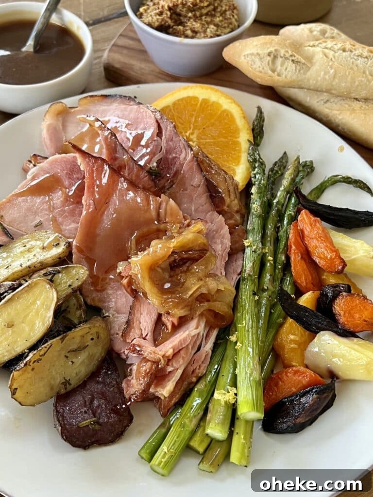 Dutch Oven Spiral Ham with Marsala Glaze Recipe 4 Baked spiral ham plated on a white dinner plate with asparagus, potatoes, carrots and orange slices, with mustard, additional glaze and bread in background.