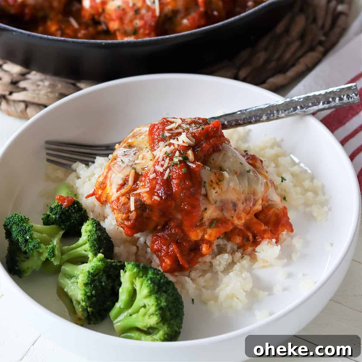 feature image of chicken parmesan casserole served on a white plate with a side of steamed broccoli.