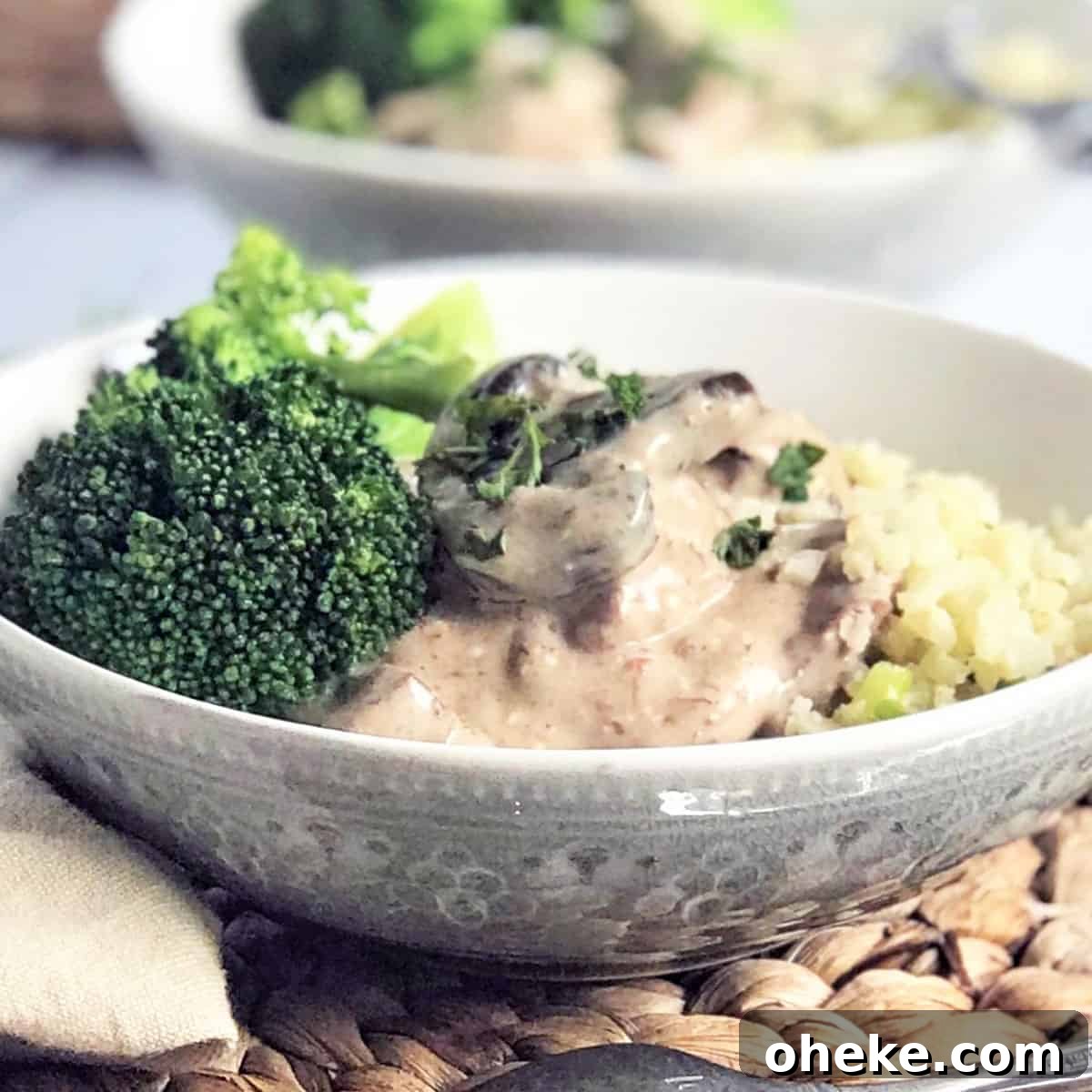 Featured image of beef stroganoff served in a gray bowl with a side of broccoli and garnished with parsley.