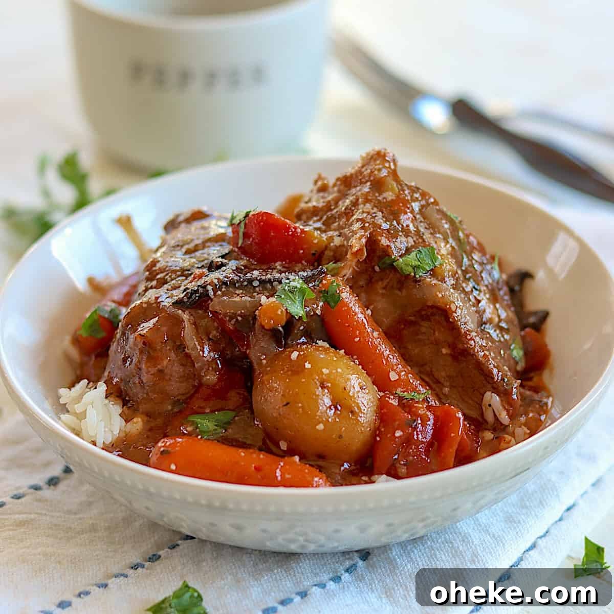 A gray bowl of crock pot roast served over rice with carrots and potatoes.