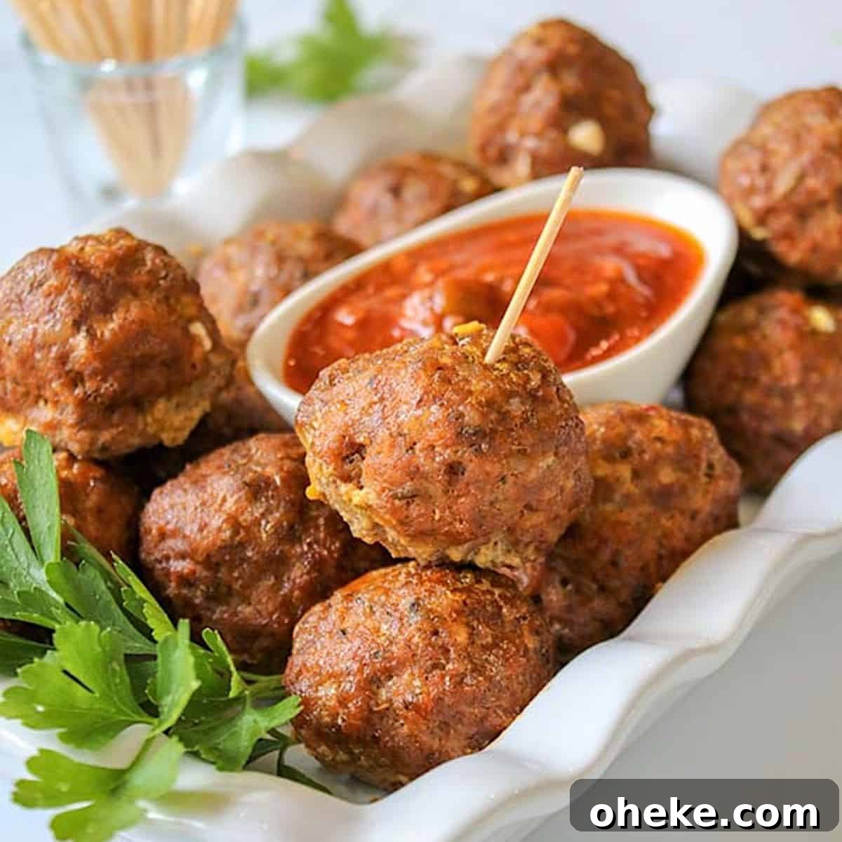Cheese stuffed meatballs on a white plate with marinara sauce for dipping