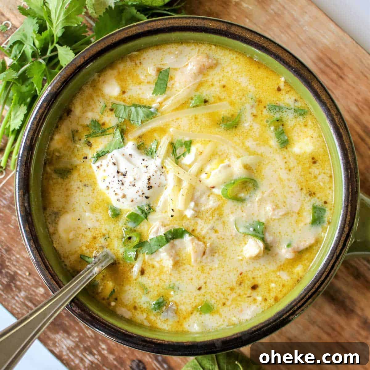 Square image of soup in a group bowl and garnished with sour cream, extra cheese, and cilantro.