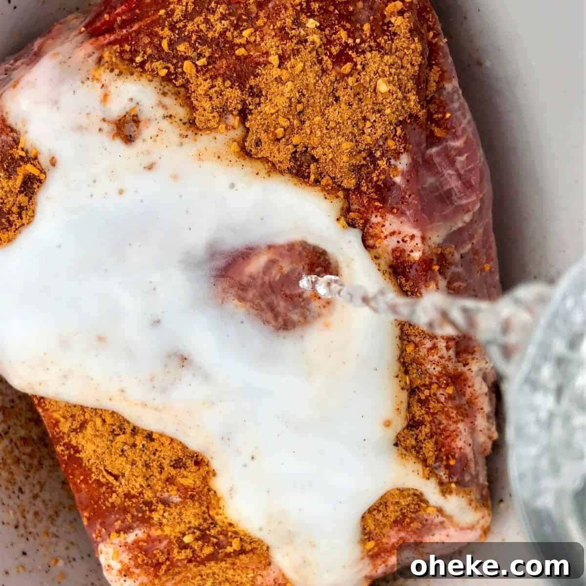 Square feature image of a pork butt roast sitting in a slow cooker and sprinkled with seasoning.
