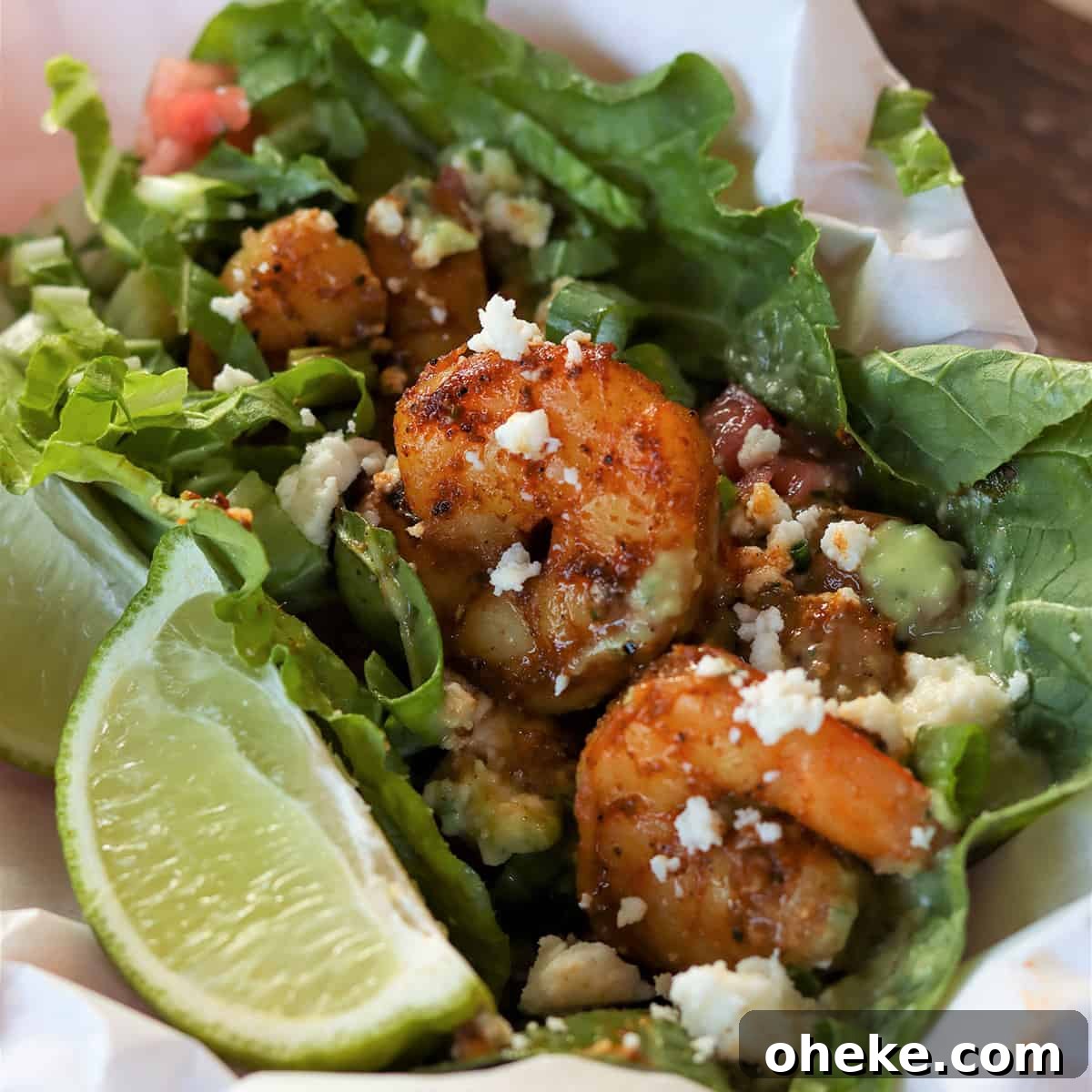 Feature image with a closeup of shrimp served in lettuce and garnished with a wedge of lime, cheese, and dressing