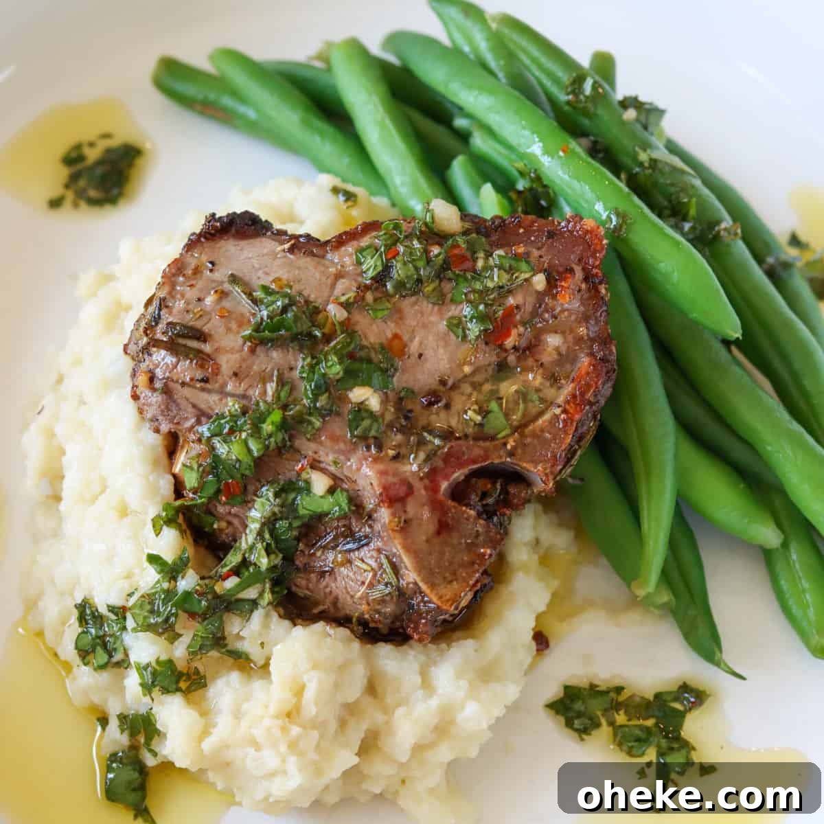An air fried lamb chop served on top of mashed cauliflower with a side of green beens and topped with mint chimichurri