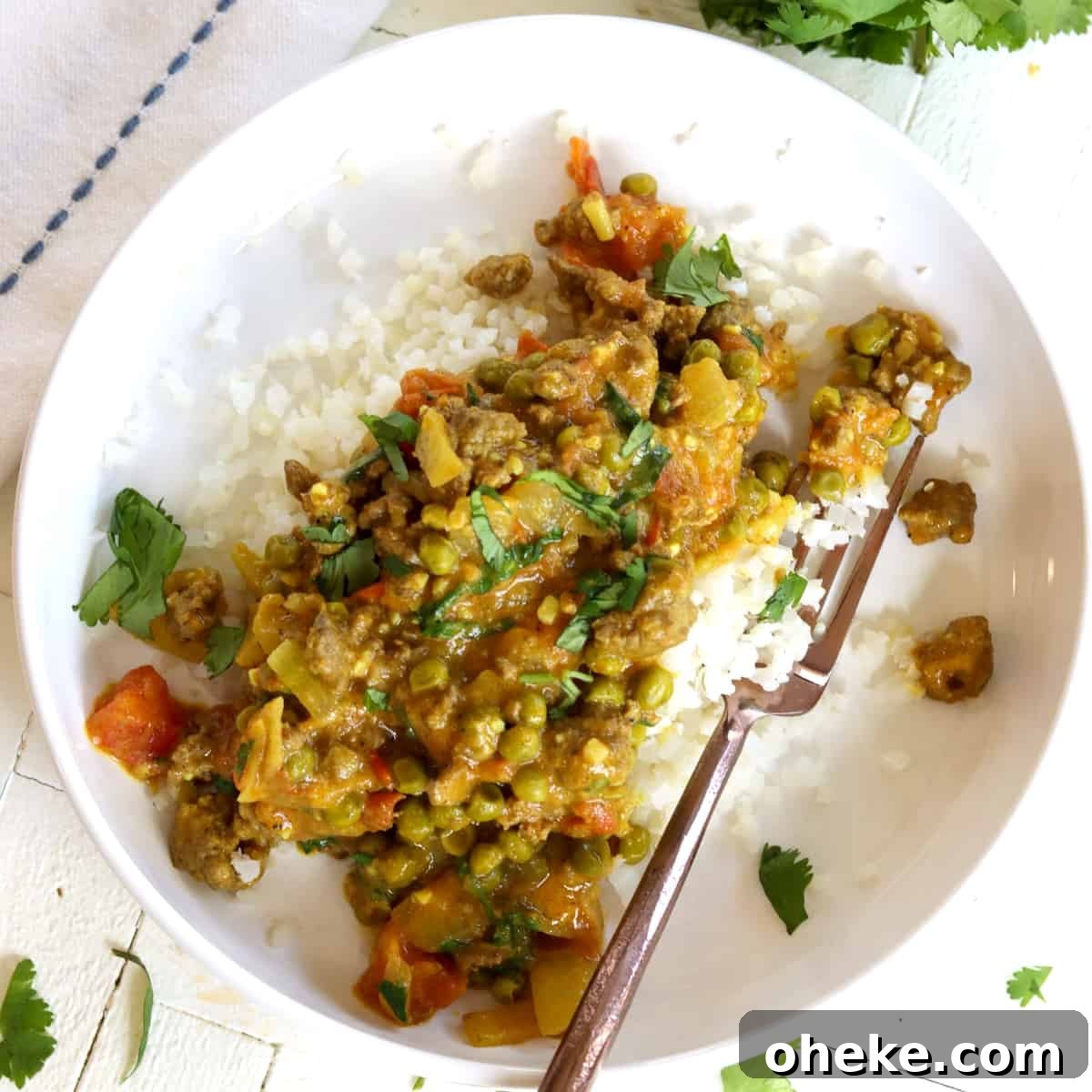 Square image of colorful lamb korma curry served in a white bowl.