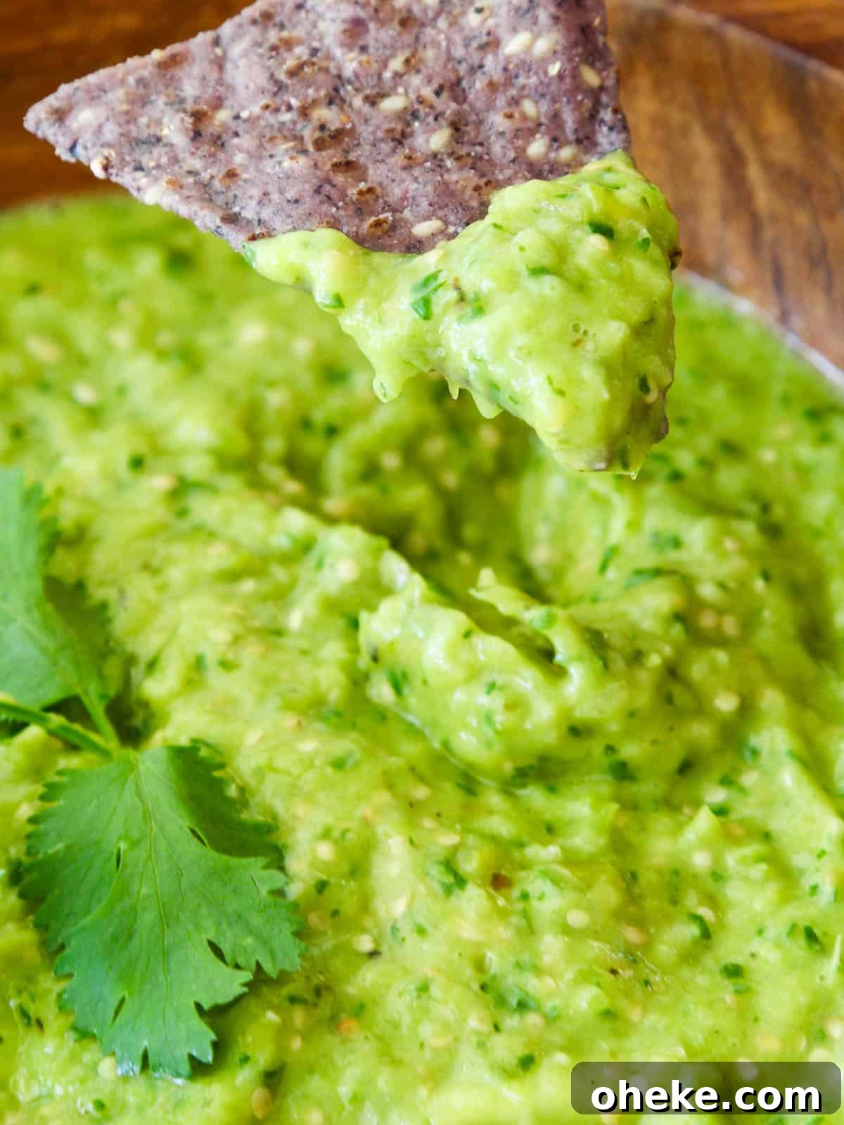 Blue tortilla chip dipping into avocado salsa