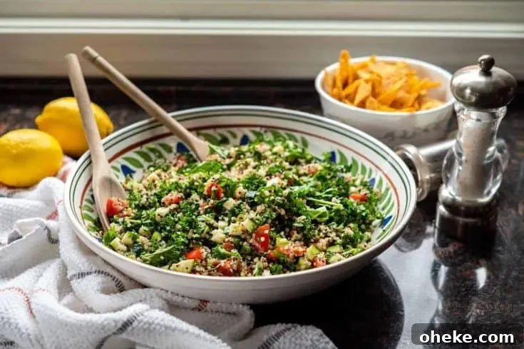 Image of kale quinoa tabbouleh salad in a large ceramic bowl, on granite countertop.