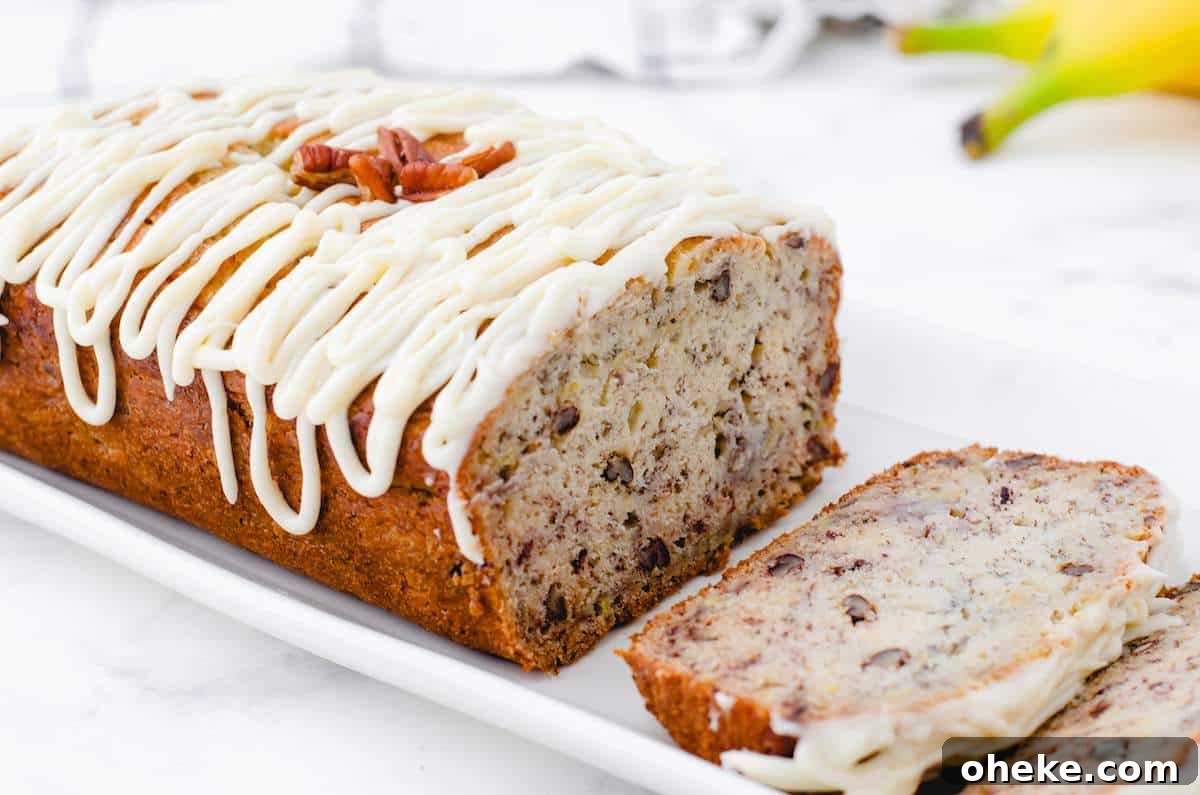 Moist Buttermilk Banana Bread Recipe with Brown Butter Glaze 2 A loaf of sliced buttermilk banana bread with nuts with frosting drizzled on the top.