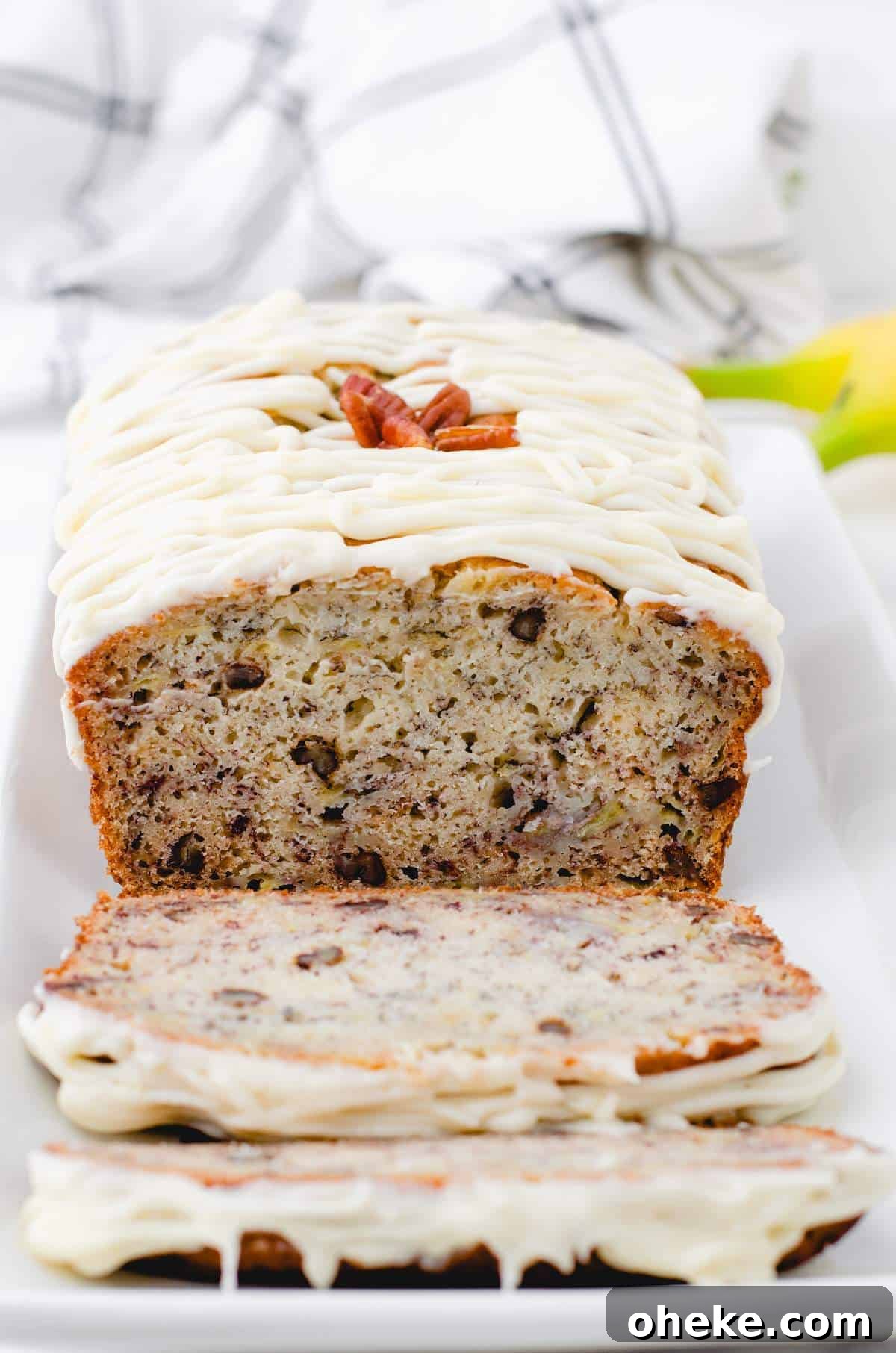 Moist Buttermilk Banana Bread Recipe with Brown Butter Glaze 8 A cross section of buttermilk banana bread on a plate with cream cheese frosting on the top.