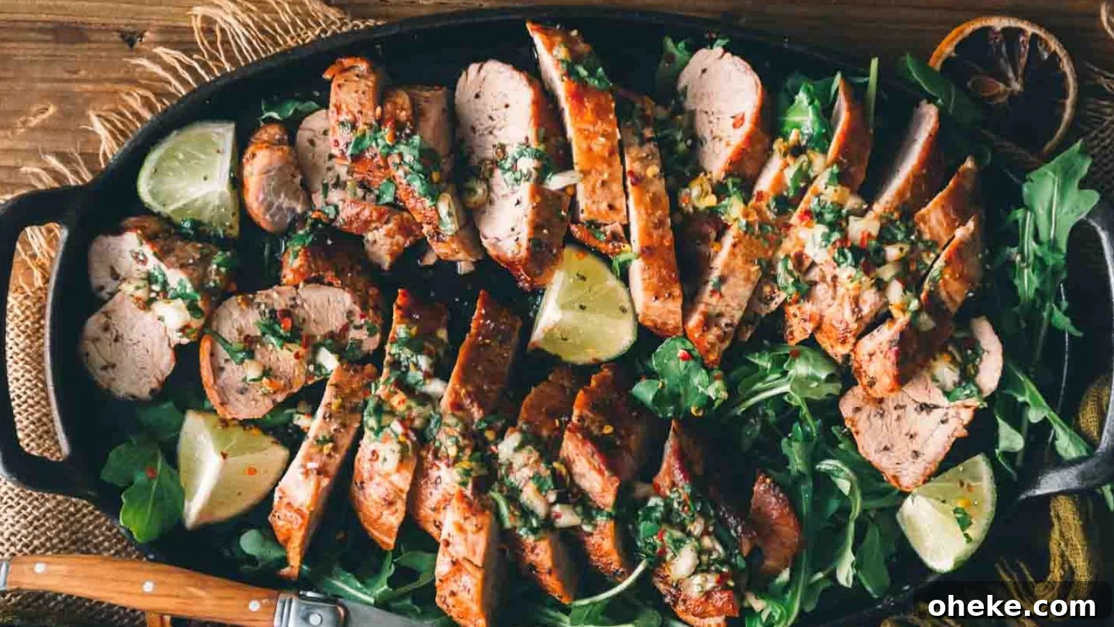 Oven-roasted pork tenderloin sliced and served with herbs on a board.