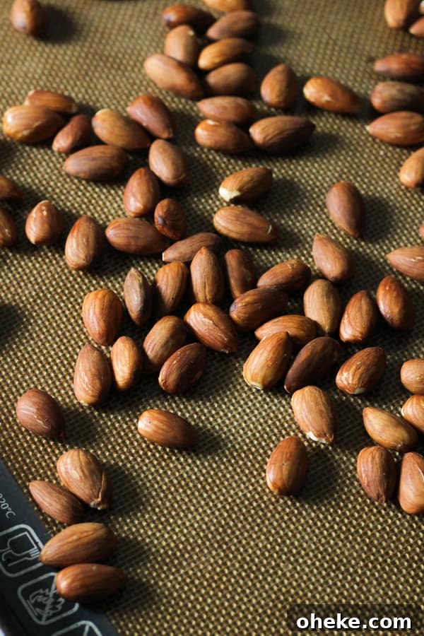 Crunchy Chocolate-Covered Almonds Recipe for Homemade Snacks 5 roasted almonds on a baking tray.