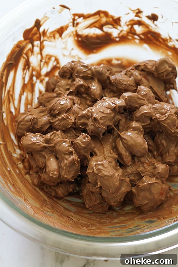 Crunchy Chocolate-Covered Almonds Recipe for Homemade Snacks 8 almonds covered in melted chocolate in a glass bowl.
