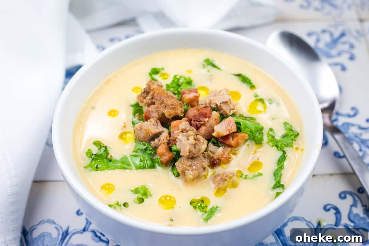 A bowl of creamy Tuscan Soup with Sausage Kale topped with kale, sausage, pancetta, and drizzles of oil.