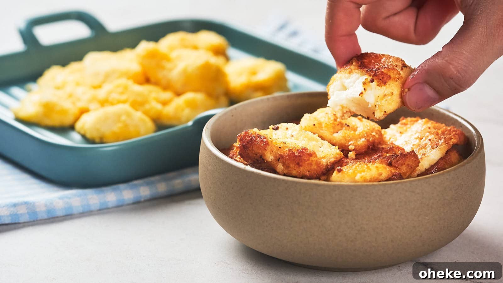 17 Comforting Recipes to Keep You Warm This Season 10 A hand picks up a piece of fried cheese curd from a bowl.