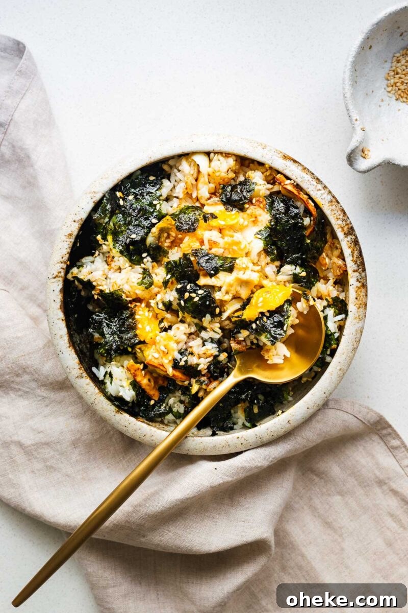 Spicy Gochujang Korean Noodles Recipe 14 A bowl of gyeran bap with everything mixed together using a golden spoon. The runny yolk coats the plump rice kernels.