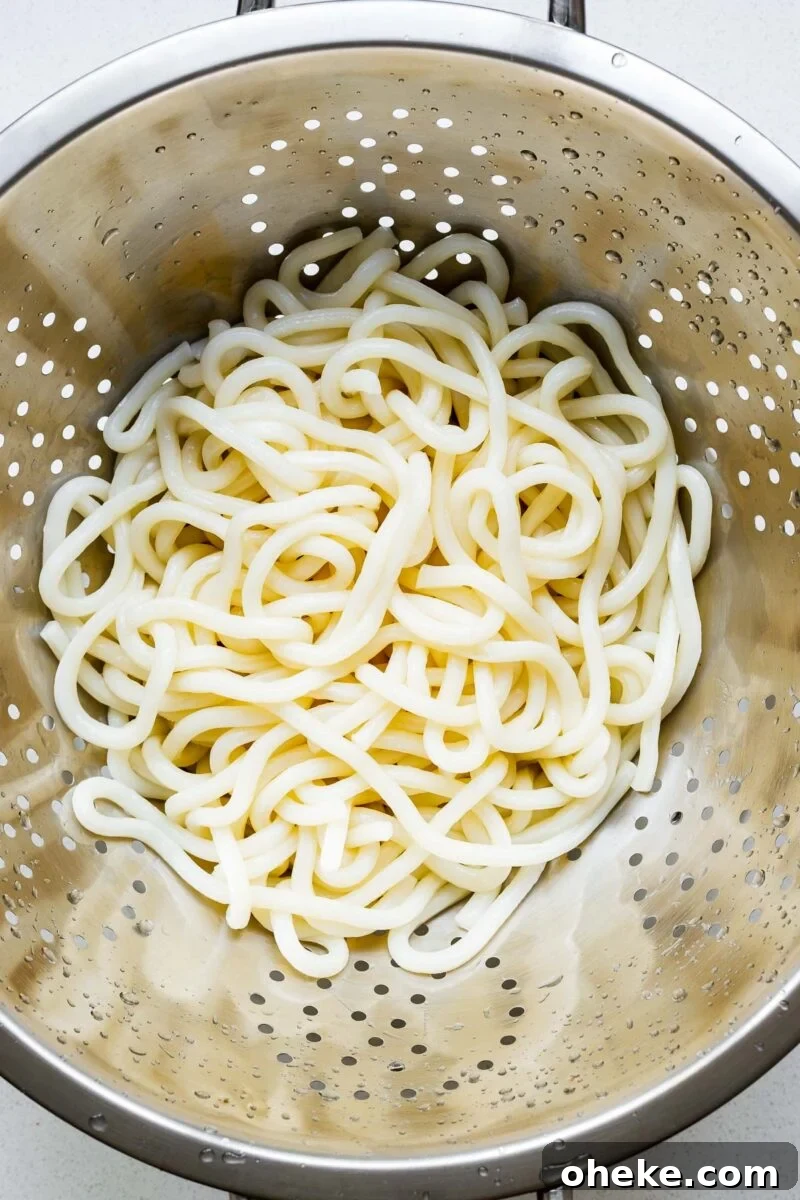 Spicy Gochujang Korean Noodles Recipe 8 Cooked udon noodles in a strainer.