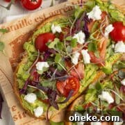 This is a square picture of an avocado toast with tomato and goat cheese.