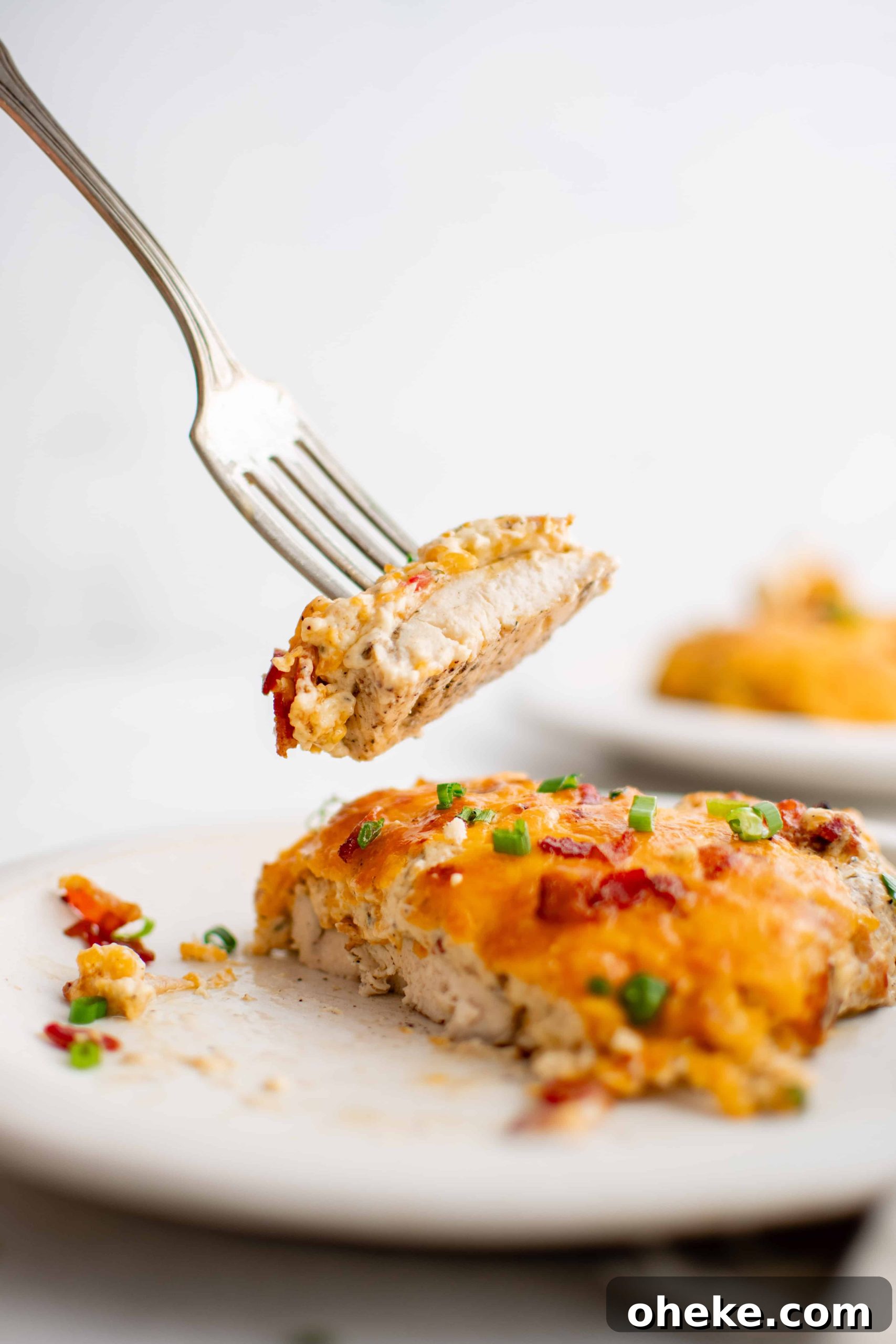 White plate filled with a baked chicken breast covered with 'crack' chicken mixture.
