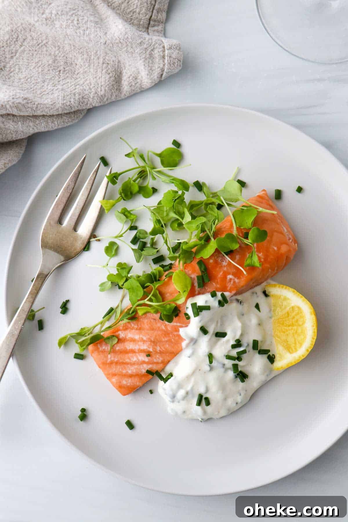 Creamy Horseradish Yogurt Sauce With 3 Simple Ingredients 2 Overhead view of salmon, greens, horseradish yogurt sauce and a lemon wedge on a white plate next to a fork.