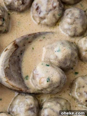 Close up of Swedish meatballs in sauce and a wooden spoon.