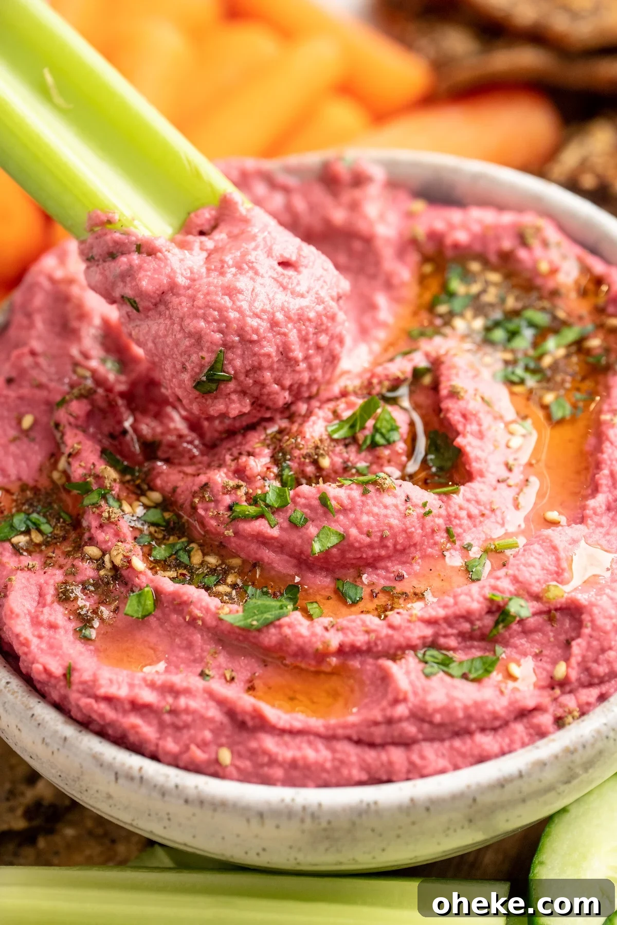 Celery scooping beet hummus from bowl Celery scooping beet hummus from bowl