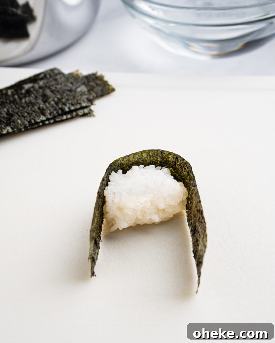 How to Make Gunkan Sushi: Step-by-Step Recipe and Tips 7 Wrapping the mound of rice with a strip of nori.