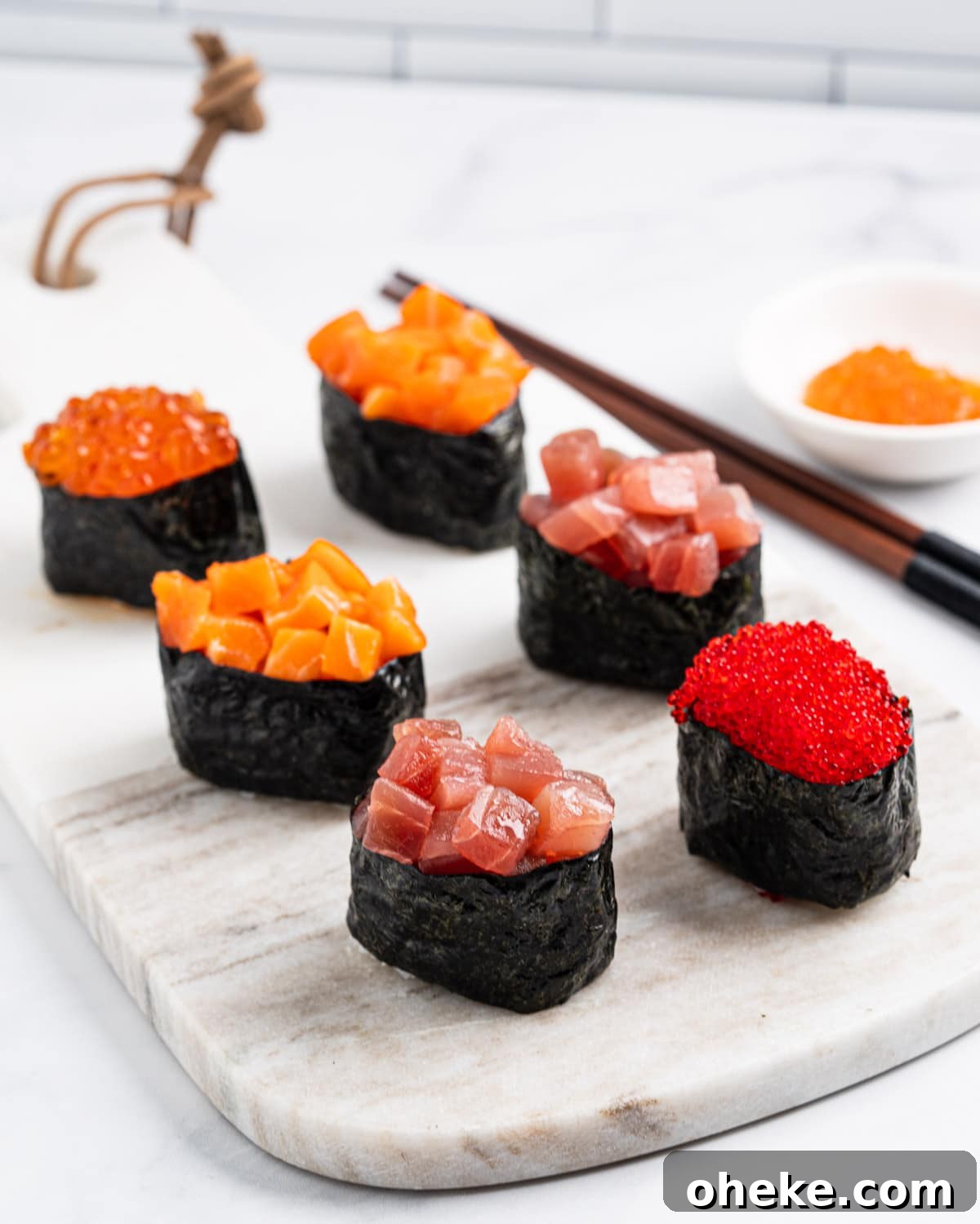 How to Make Gunkan Sushi: Step-by-Step Recipe and Tips 9 side angle of 6 gunkan on a marble serving board: 1 tobiko gunkan, 2 tuna gunkans, 2 salmon gunkans and 1 ikura gunkan.
