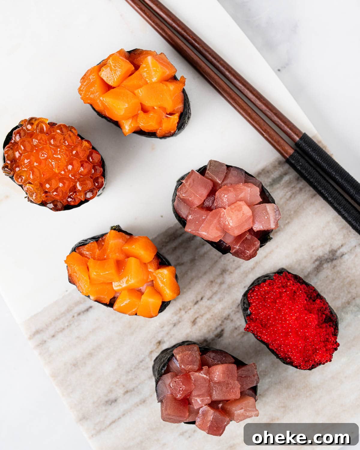 How to Make Gunkan Sushi: Step-by-Step Recipe and Tips 10 top down angle of 6 gunkan on a marble serving board: 1 tabiko gunkan, 2 tuna gunkans, 2 salmon gunkans and 1 ikura gunkan.