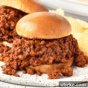 A close-up of a Sloppy Joe sandwich with seasoned ground beef spilling out of a bun.