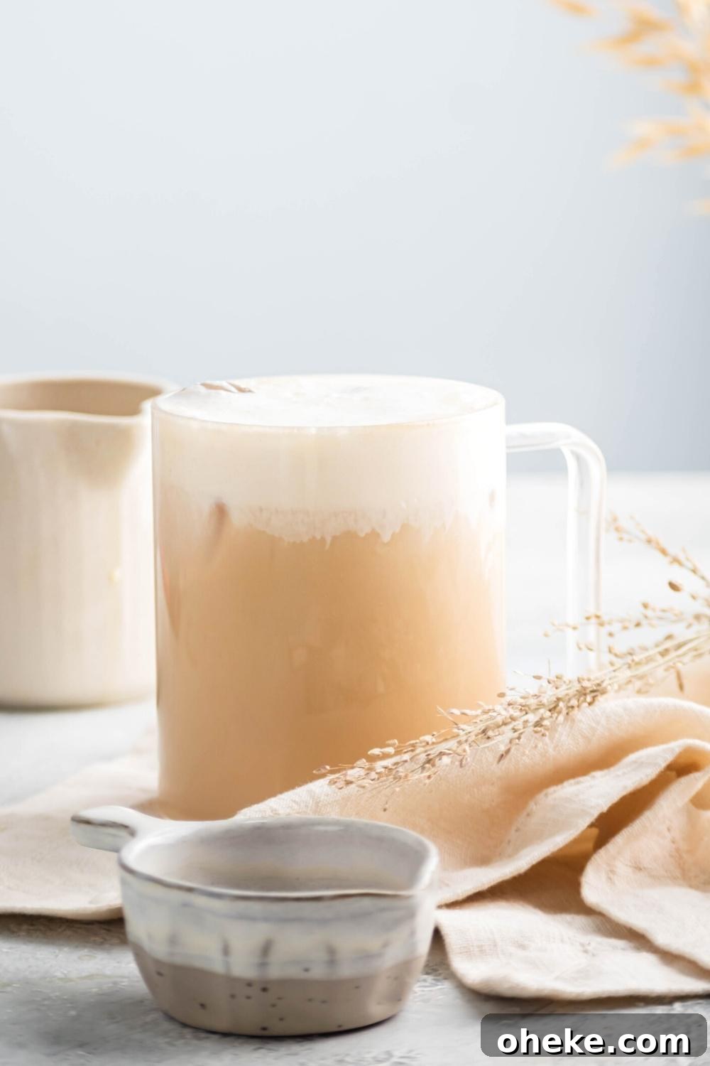 Starbucks Iced White Chocolate Mocha Copycat Recipe — How to Make at Home 7 An ice white chocolate mocha and a glass cup on a white napkin on a gray counter.