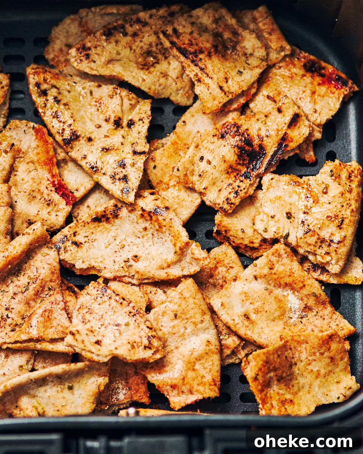 Pita chips in an air fryer basket before baking.