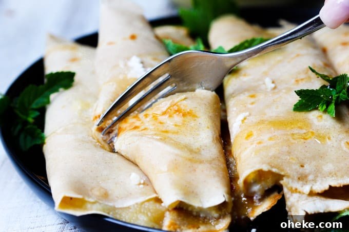 These Apple Sauce Crepes with Honey Ricotta are made with cinnamon crepes, North Coast Organic Apple Sauce, organic ricotta and raw honey. These crepes are super delicious and healthy at the same time. A perfect option for a school lunch or an afternoon snack. Fork cutting through crepe with apple sauce and ricotta with honey