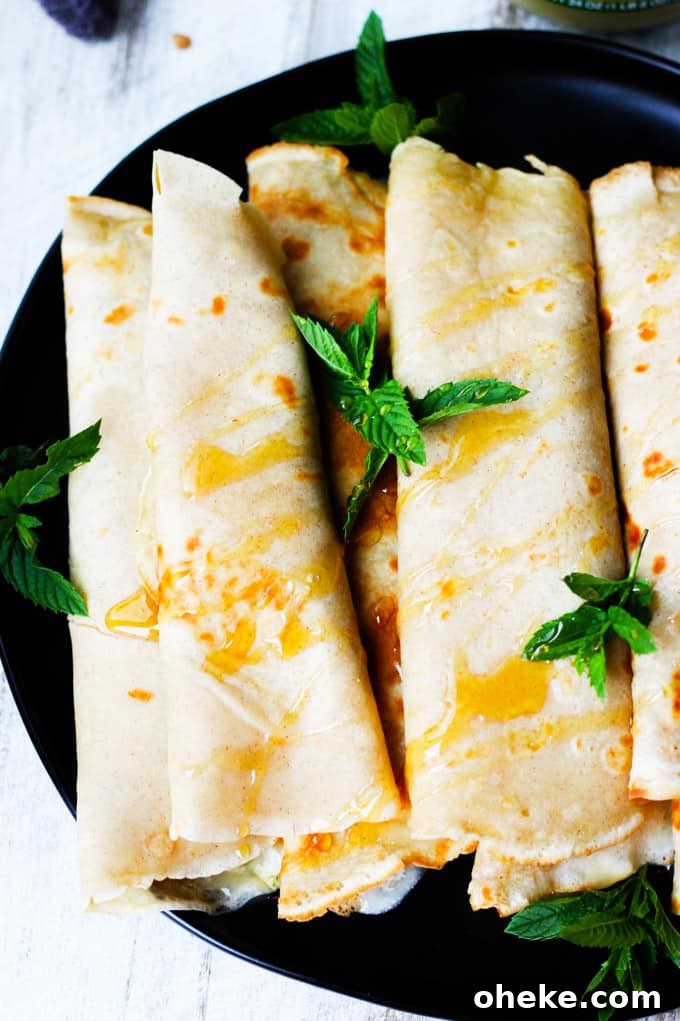 These Apple Sauce Crepes with Honey Ricotta are made with cinnamon crepes, North Coast Organic Apple Sauce, organic ricotta and raw honey. These crepes are super delicious and healthy at the same time. A perfect option for a school lunch or even an afternoon snack. Apple Sauce Crepes with Honey Ricotta rolled on a black plate