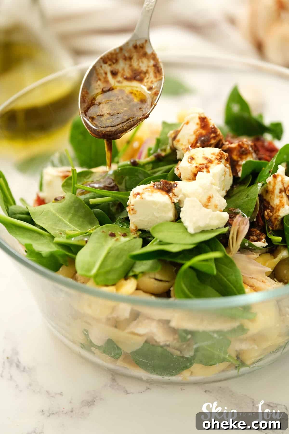 adding dressing to the tortellini salad