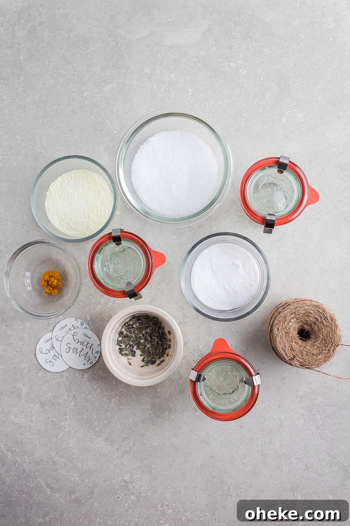 A table with various ingredients for a homemade herbal bath salts recipe.