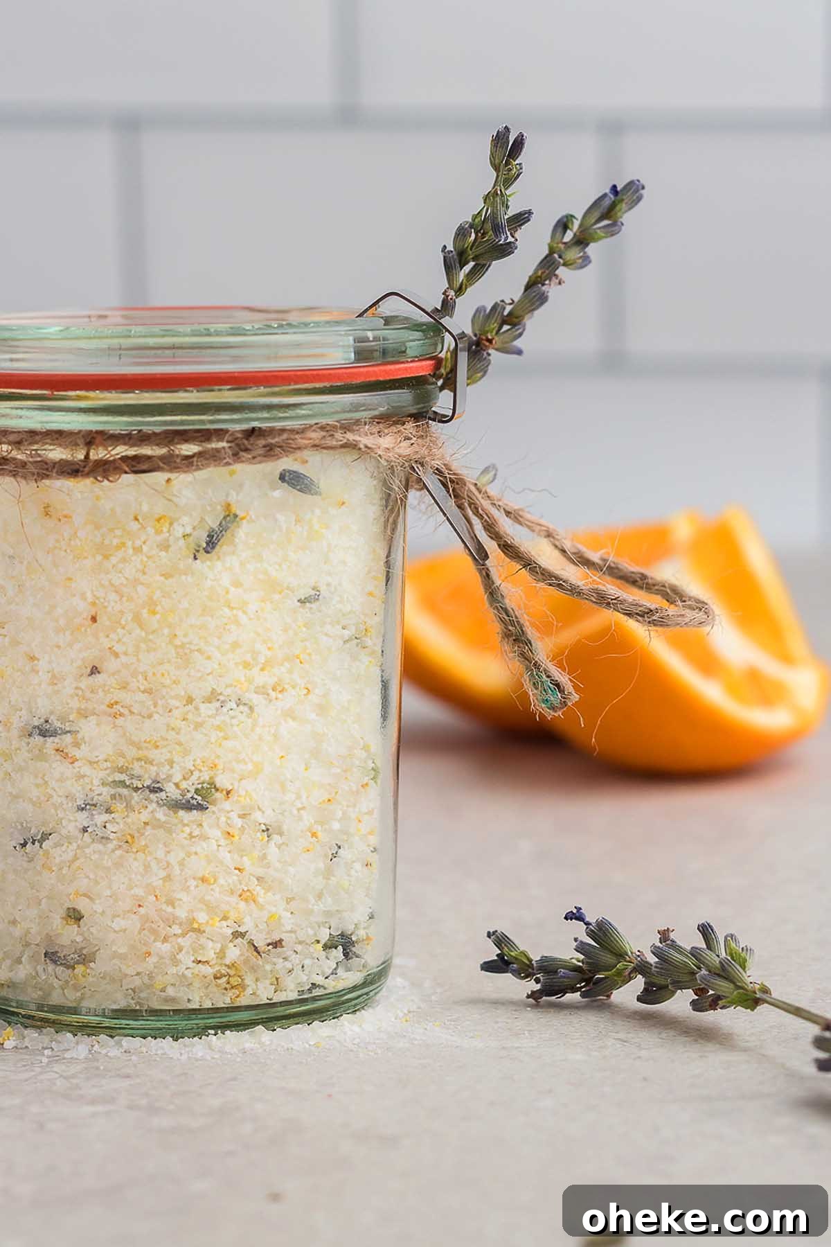 A homemade bath salts gift jar featuring herbal bath salts, paired with an orange slice.