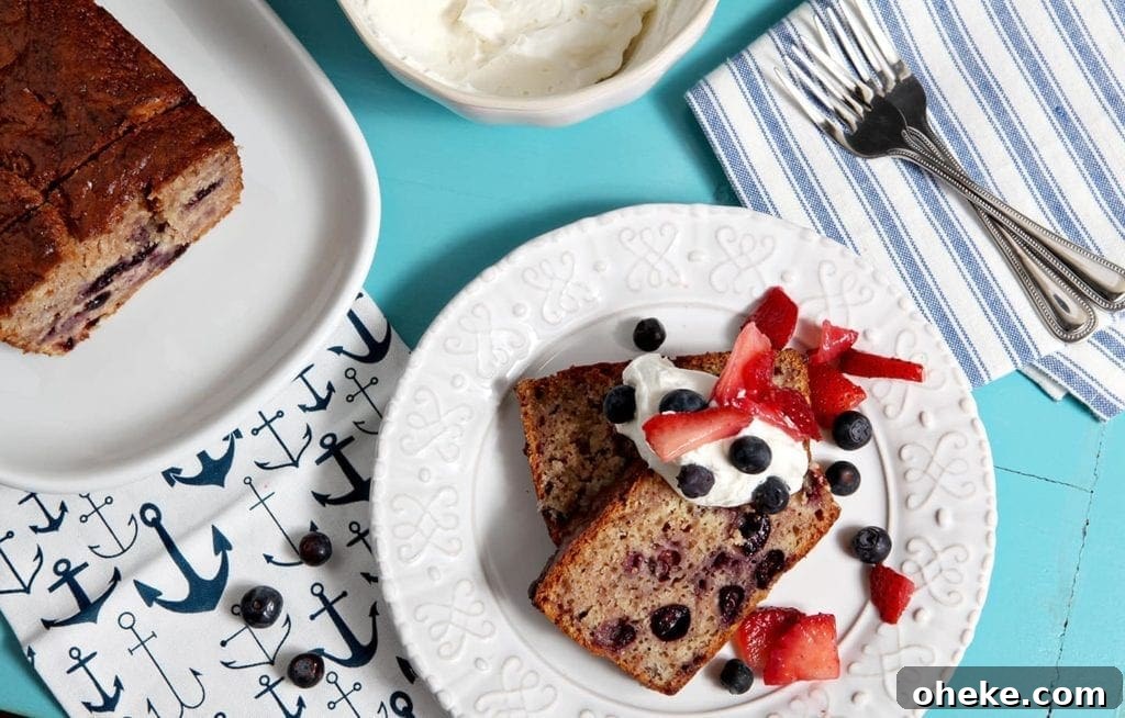 Two slices of berry pound cake are served with homemade whipped cream, blueberries and sliced strawberries