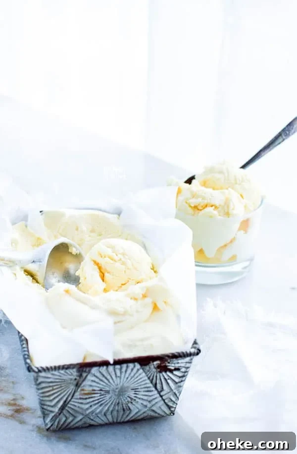 homemade vanilla ice cream being scooped from a silver pan with a bowl of ice cream already scooped in the background